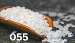 Raw rice grains in a wooden scoop, close-up view