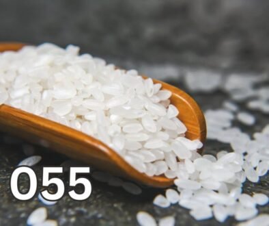 Raw rice grains in a wooden scoop, close-up view