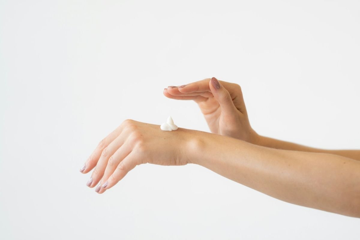 Close-up of a woman’s hand applying hand cream, illustrating intentional self-care and a quiet commitment to well-being.