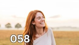 Smiling woman in casual white shirt and jeans standing in a sunlit grassy field