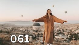 Woman smiling with open arms outdoors symbolising freedom, confidence, and a positive mindset.