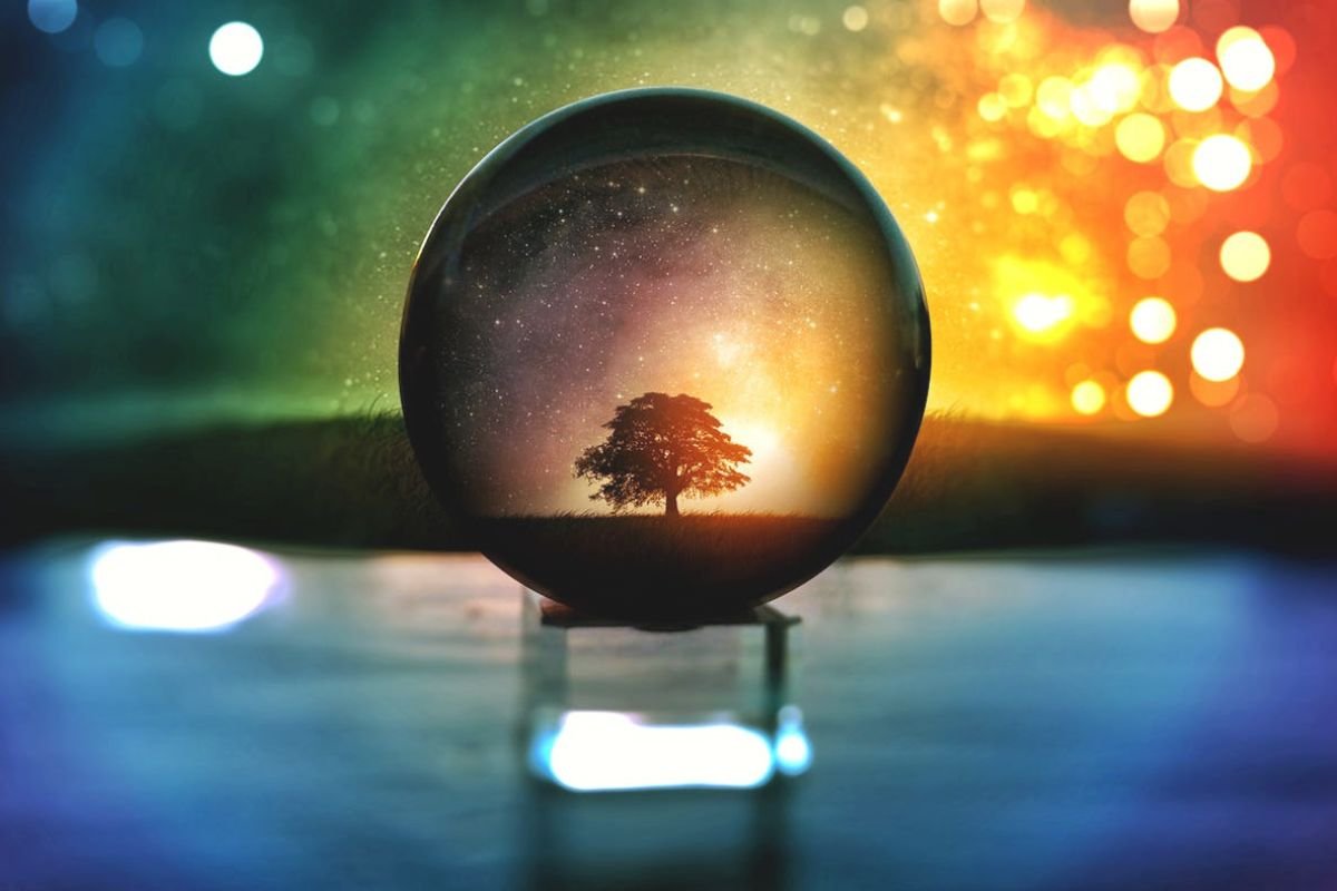 Crystal ball showing a miniature tree under starry bokeh lights