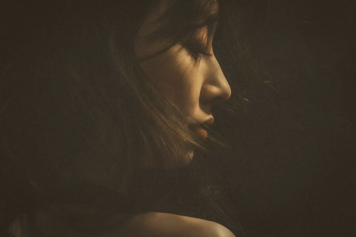 Woman with eyes closed, soft light on her face, beautiful serene expression