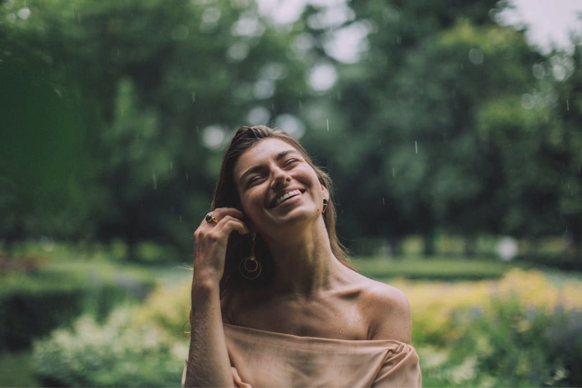 Woman smiling joyfully in the rain, embracing positivity and choosing happiness.