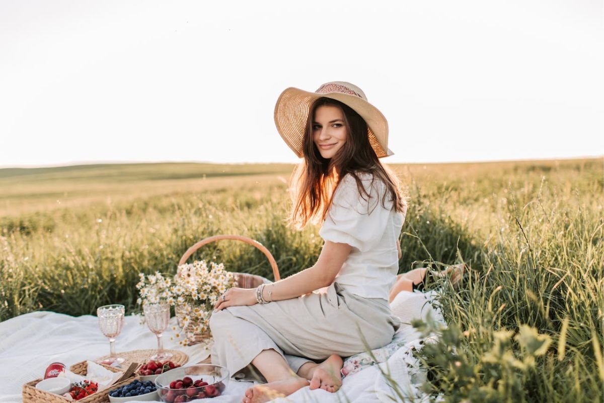 Woman smiling peacefully on a grass field, symbolising happiness, mindfulness, and positive habits.