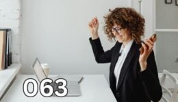 Happy woman raising arms at work desk, celebrating success and finding joy by treating work as a meaningful hobby.