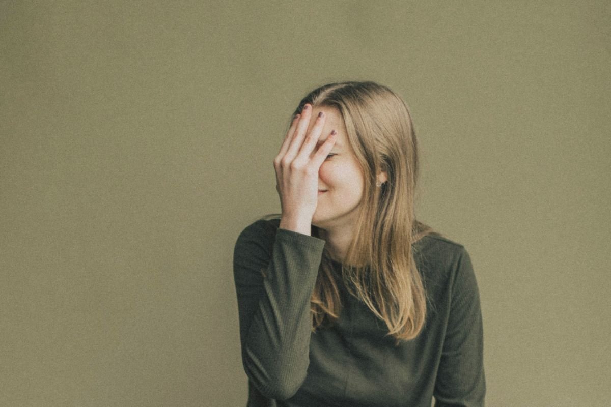 Woman covering her face with hand, feeling shy or embarrassed