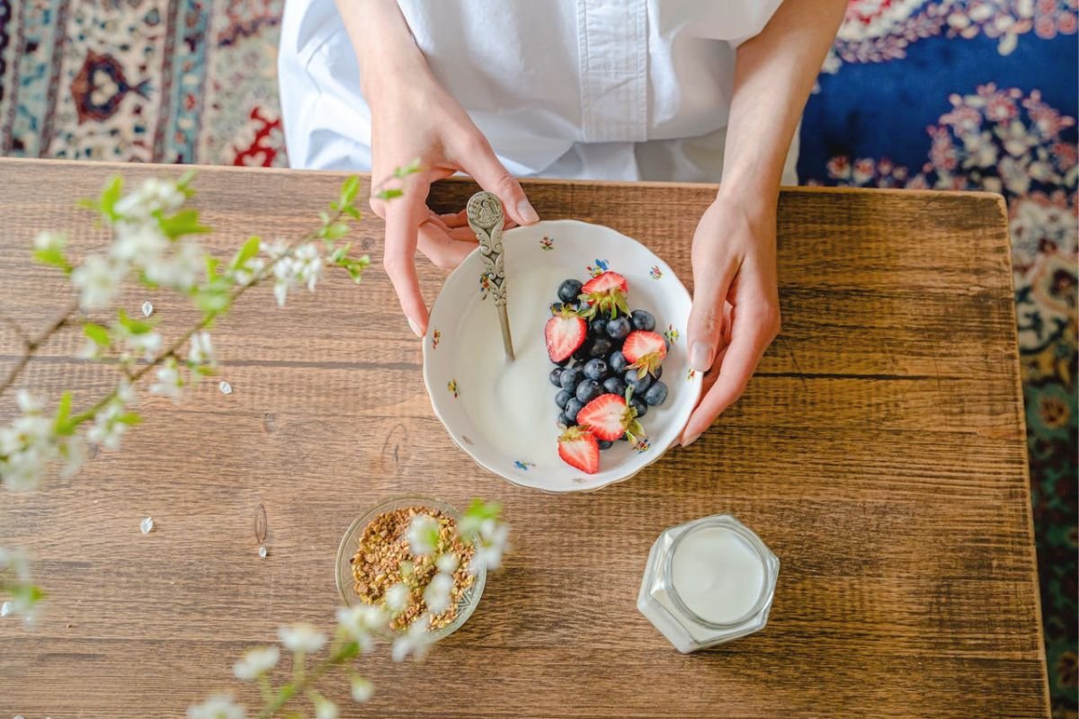 Hands holding a bowl of yoghurt with berries, representing probiotic and gut health