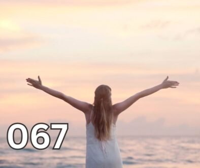 Rear view of a woman standing alone at the beach during sunset with arms raised, symbolising independence and inner peace in later life.