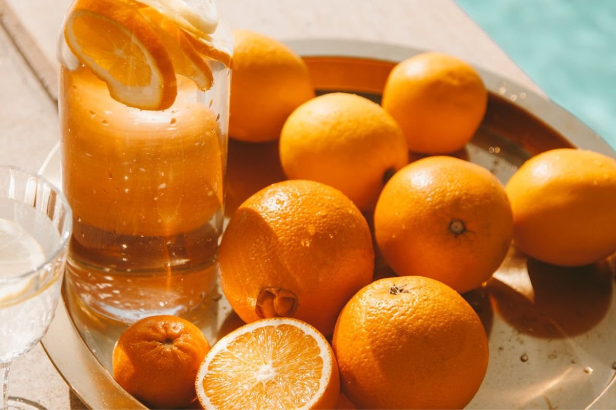 Pitcher of orange juice beside fresh oranges