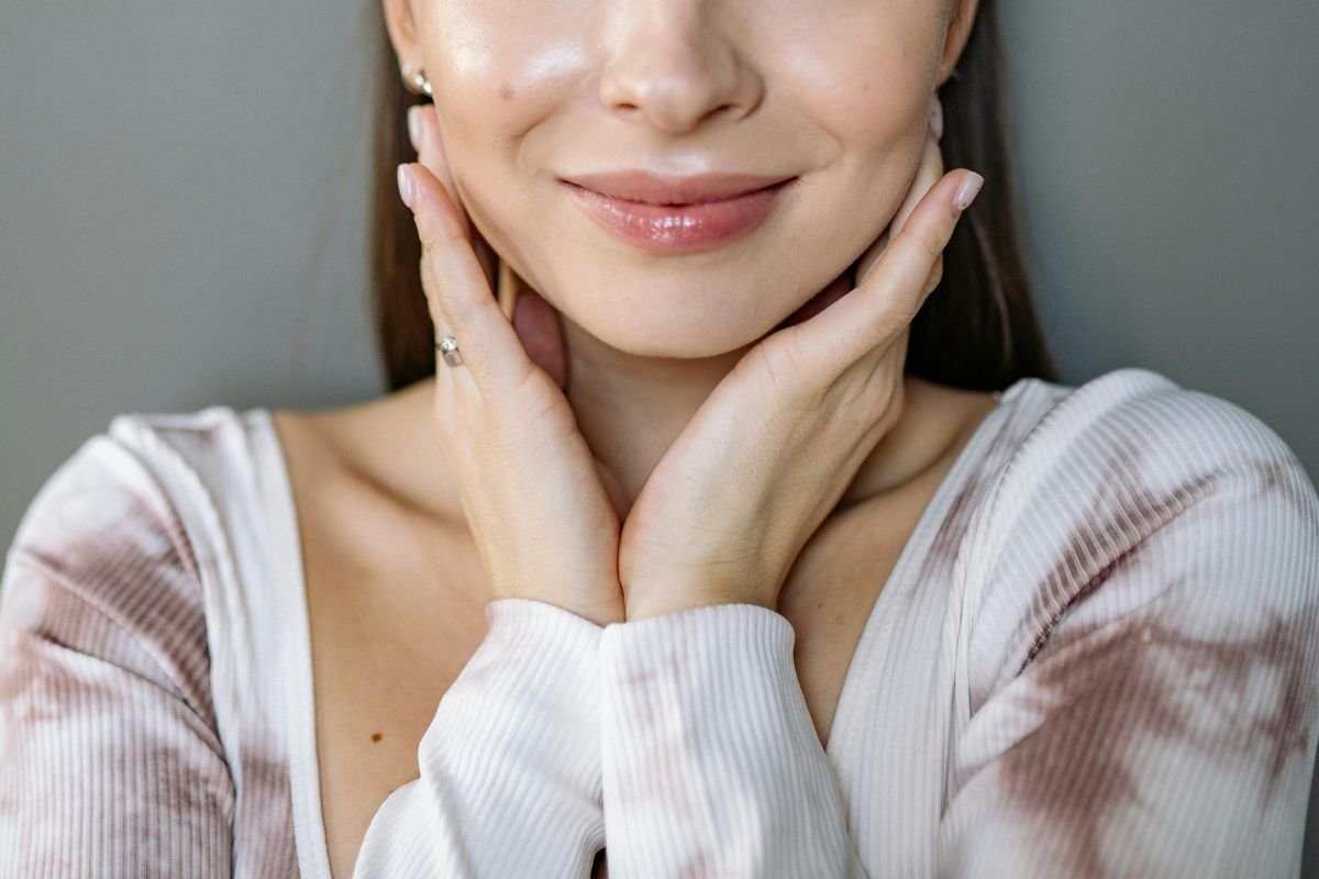 Close-up of woman touching her face with glowing clear skin