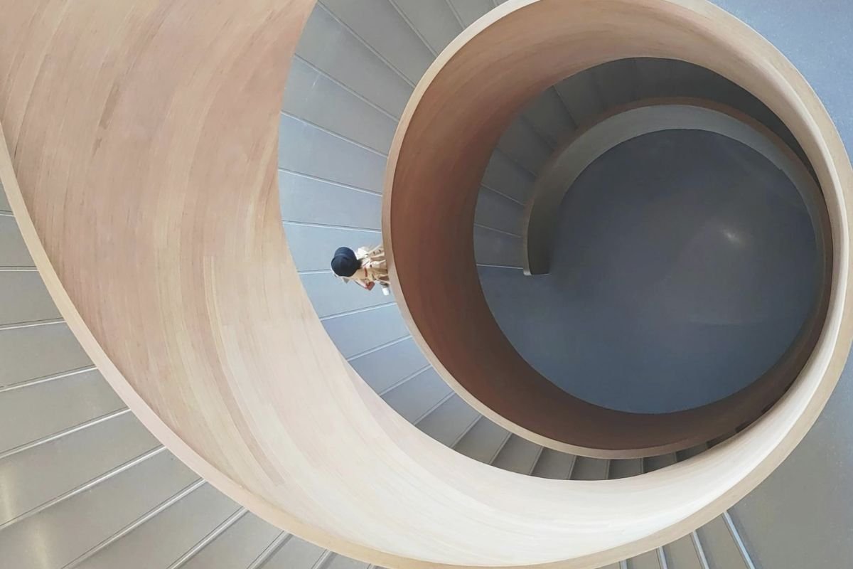 Woman walking on spiral stairs, symbolising the repetitive thought cycles of anxiety, overthinking, and obsessive behaviours.