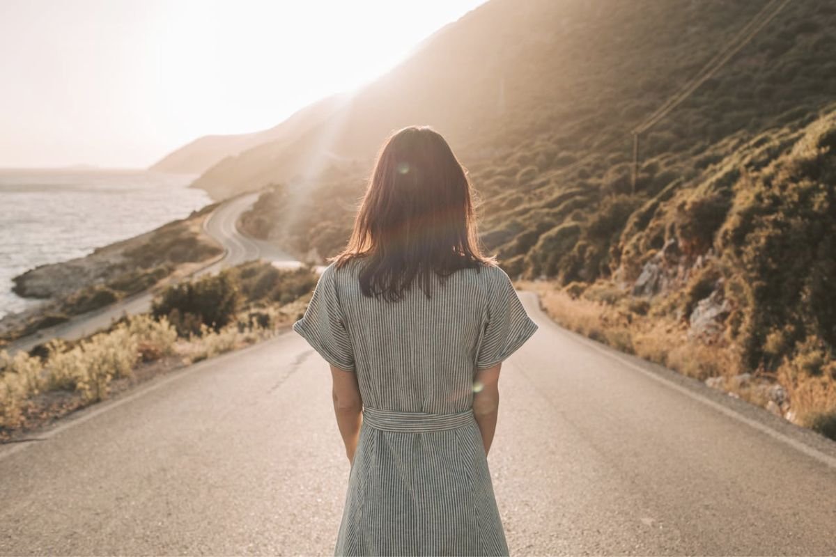 Woman standing on an empty road at sunrise, symbolising emotional freedom, healing, and clarity after overcoming inner struggle.