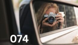 Person photographing their reflection in a rear-view car mirror