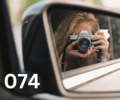 Person photographing their reflection in a rear-view car mirror