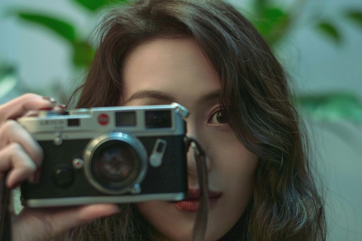 Woman holding a DSLR camera up to her face, ready to take a photo