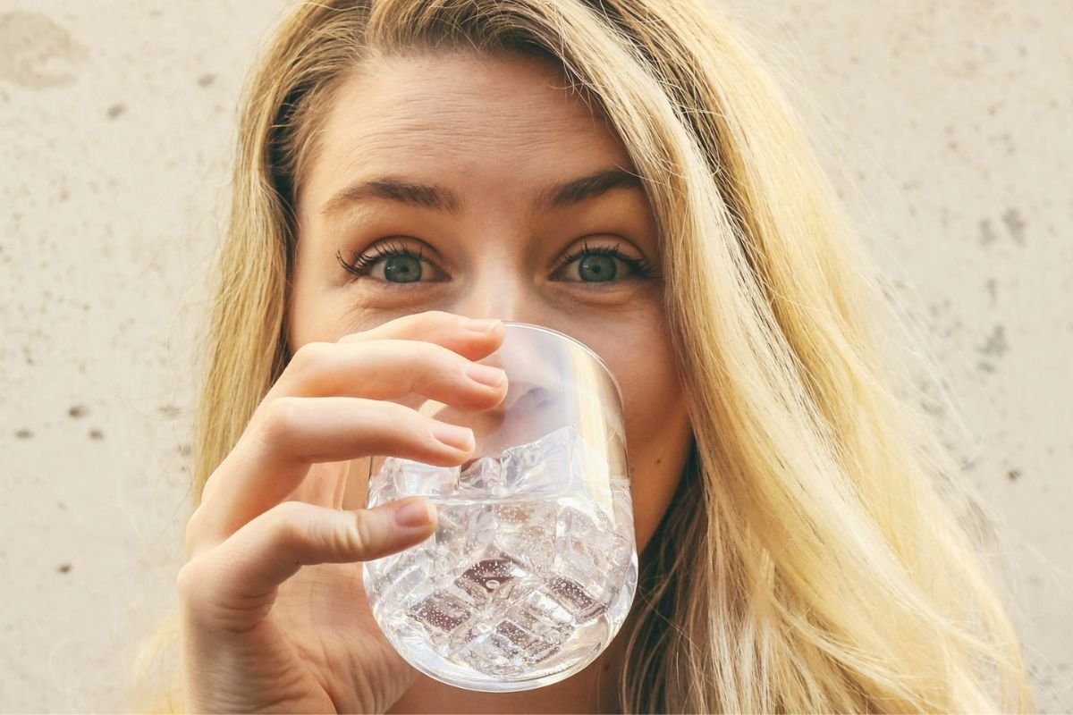 Woman in white shirt drinking water from a glass