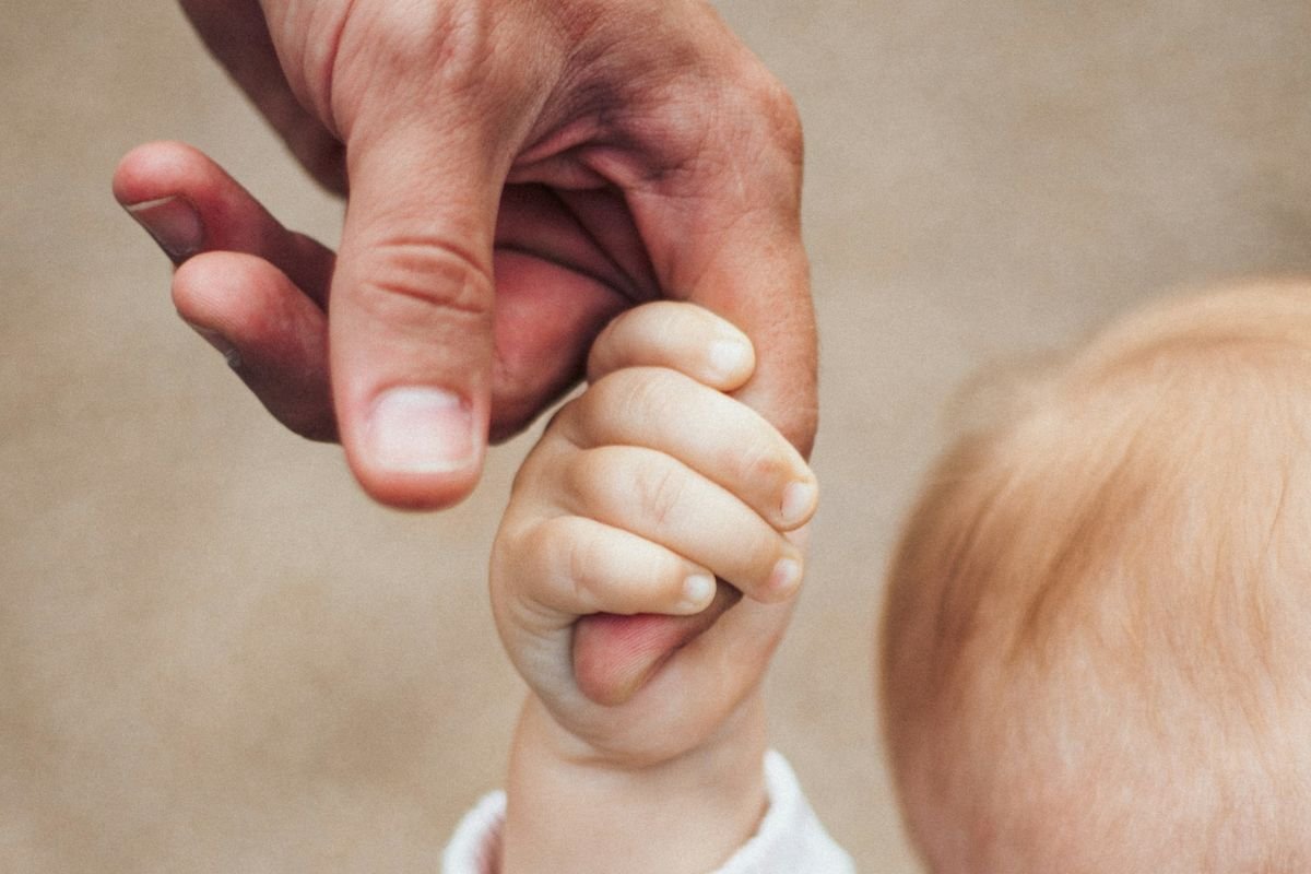 Child holding father’s hand, symbolising early emotional security and belonging