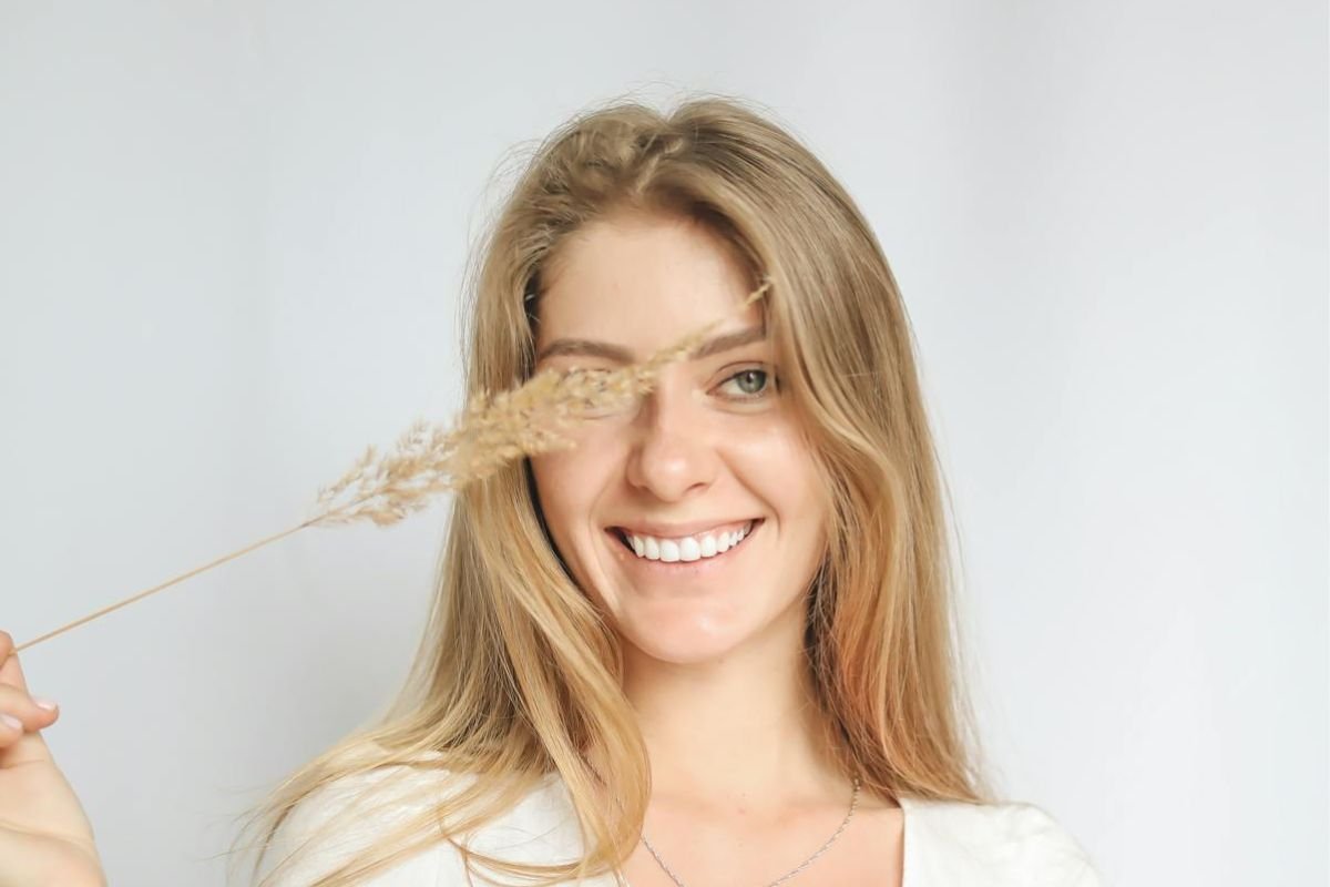 Woman holding dried grass smiling confidently, illustrating self-worth and inner strength