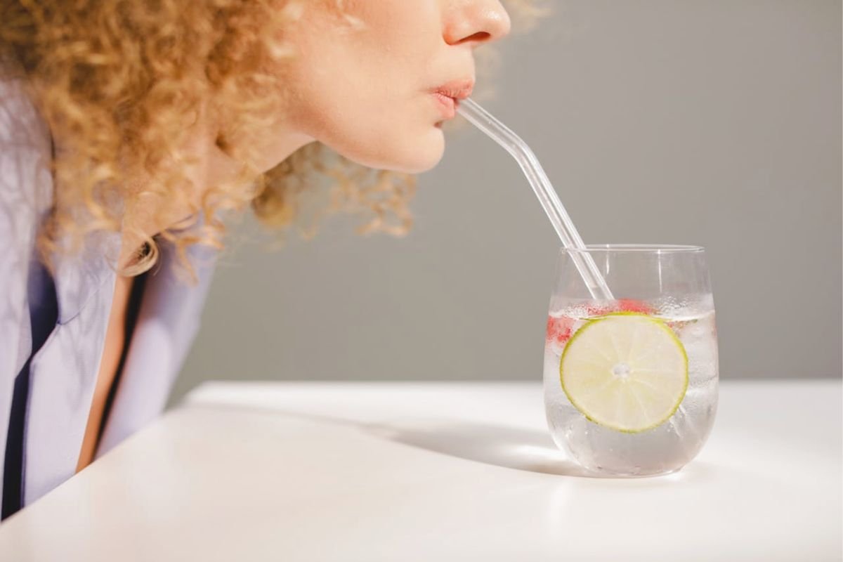 Woman sipping lemon water through a straw in natural light
