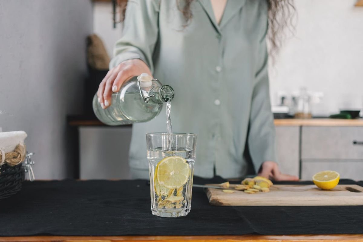 Hand pouring clear water into a glass from a jug