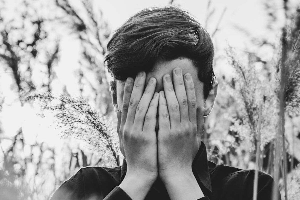 A man covering his face with his hands, reflecting emotional strain and the psychological impact of PTSD.