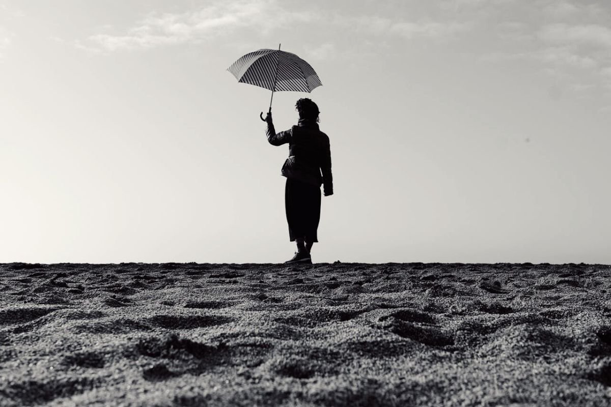Woman holding an umbrella on a rainy day, symbolising personal strength and learning to support yourself when life becomes difficult.