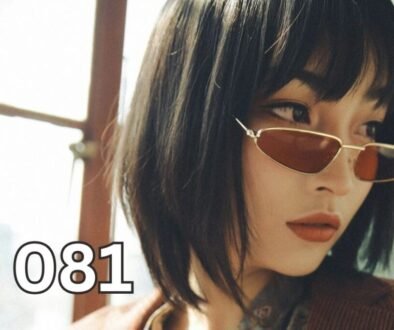 A confident woman in a brown suit jacket sitting by a window, looking thoughtful and self-determined, symbolising emotional intelligence and independence.