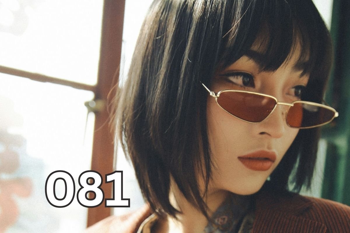 A confident woman in a brown suit jacket sitting by a window, looking thoughtful and self-determined, symbolising emotional intelligence and independence.