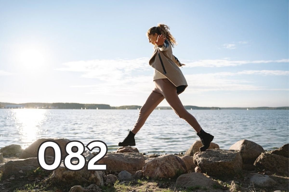 Woman balancing across coastal rocks alone, symbolising personal growth through lived experience and life lessons learned without advice.