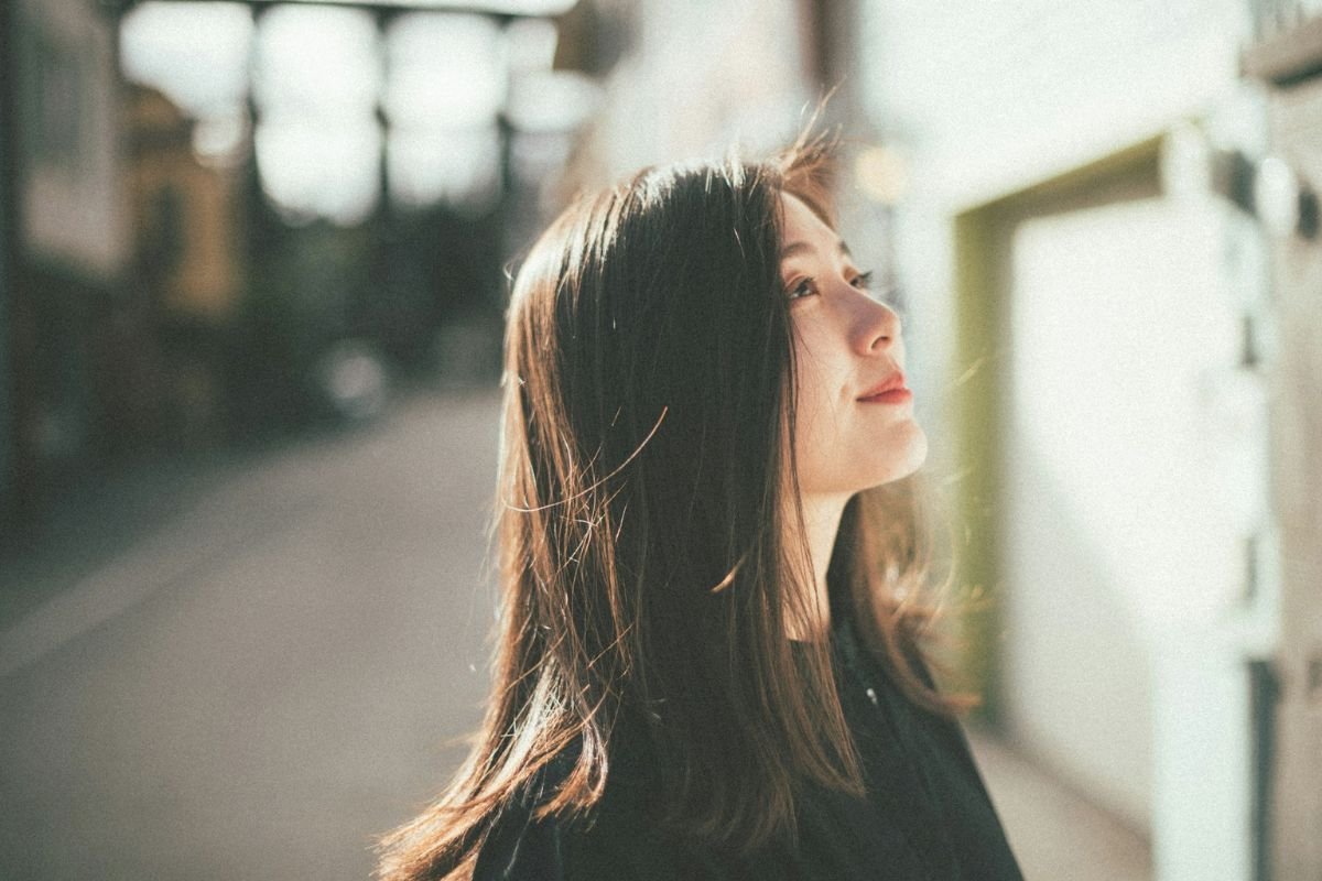 A confident woman smiling and looking upward outdoors, representing emotional intelligence and intentional choices about time, energy, and focus.