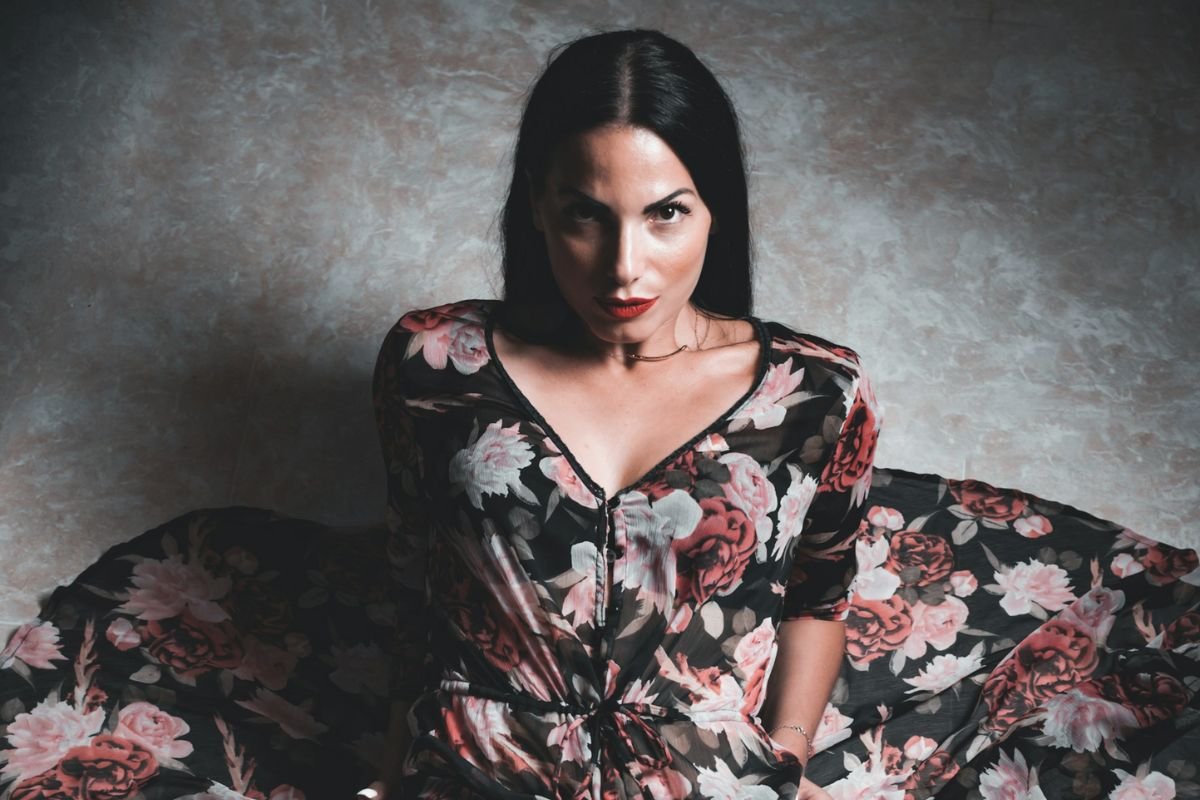 An elegant woman sitting confidently on the floor, symbolising independence, self-reliance, and dignity in choosing her own path.