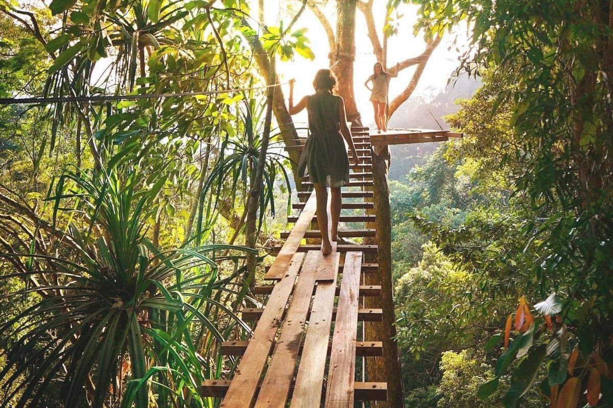 Woman crossing a bridge alone while holding a rope, representing self-led change, resilience, and personal awakening through real-life challenges.