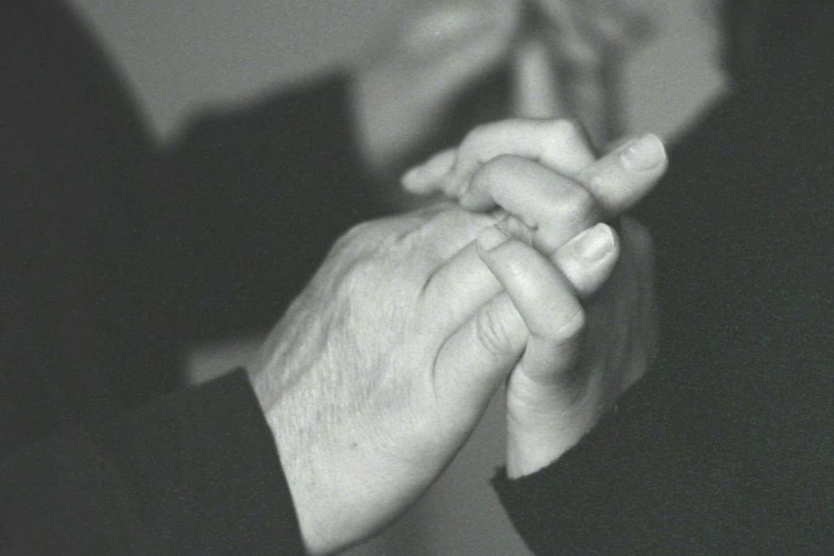 Man and woman holding hands firmly, representing lingering connection despite harm.