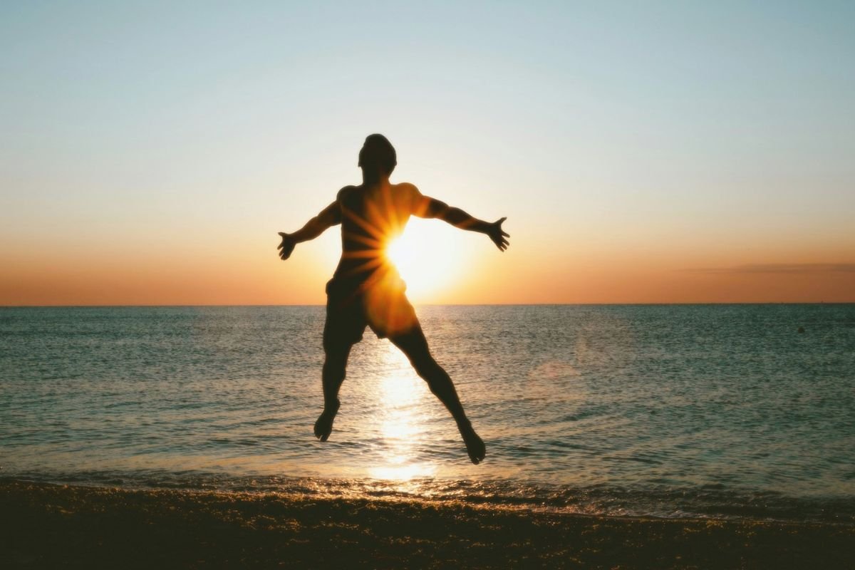 Silhouette of a man jumping on a beach at sunset, expressing physical energy, freedom of movement, and healthy circulation