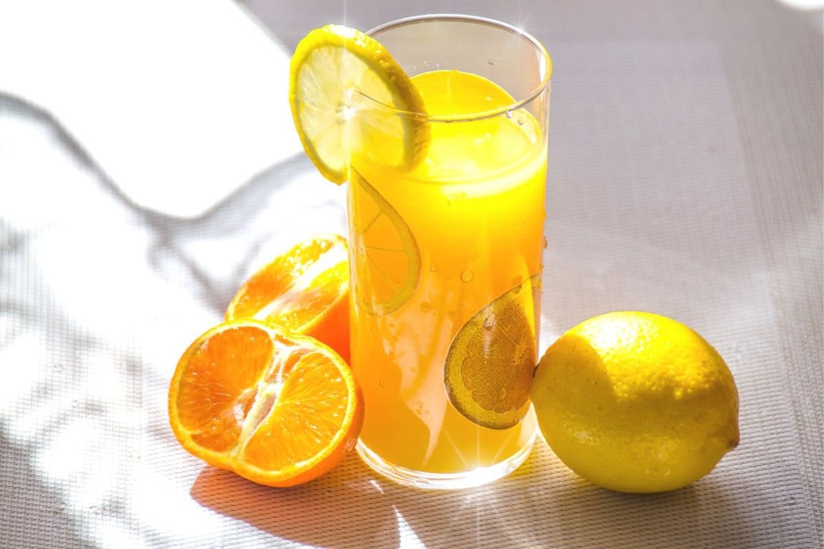 Glass of citrus juice and lemons representing vitamin C and collagen support for skin, joints, cartilage, and connective tissue