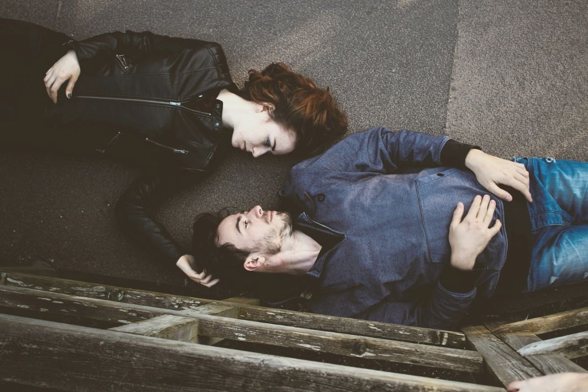 Man and woman lying face to face, representing emotional triggers in relationships and sensitivity to mistakes
