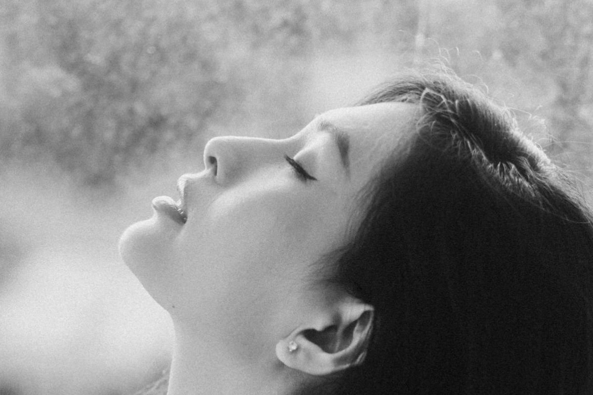 Woman with eyes closed and head raised toward the sky showing openness and calm