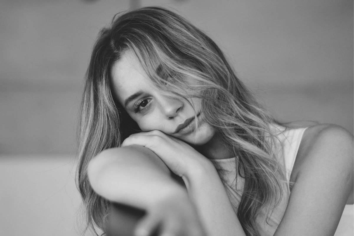 Woman resting face on hand with bored expression illustrating emotional flatness