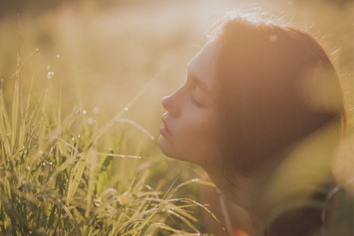 Woman with closed eyes and warm sunlight reflecting calm and hope