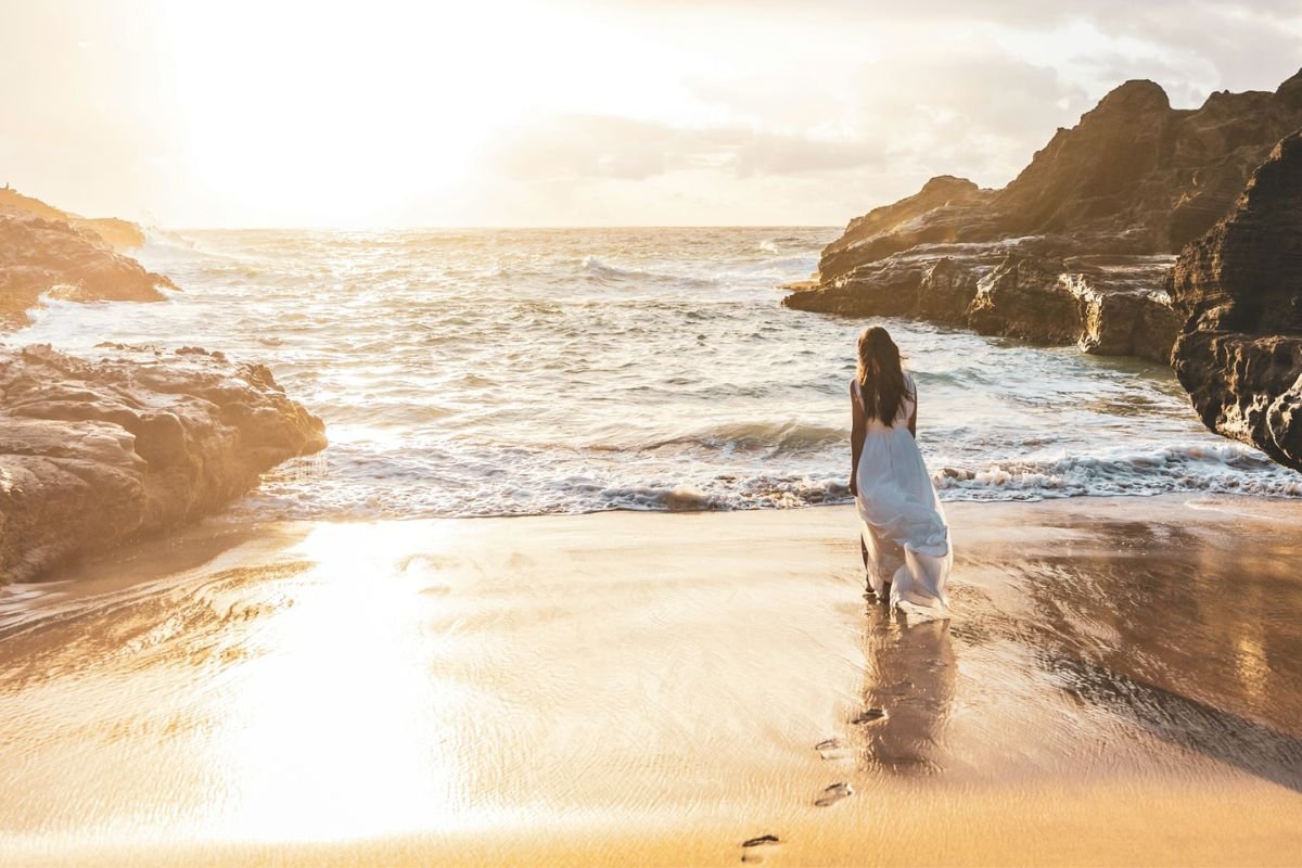 Person walking alone along the beach toward the horizon, symbolising staying true to yourself and living with integrity