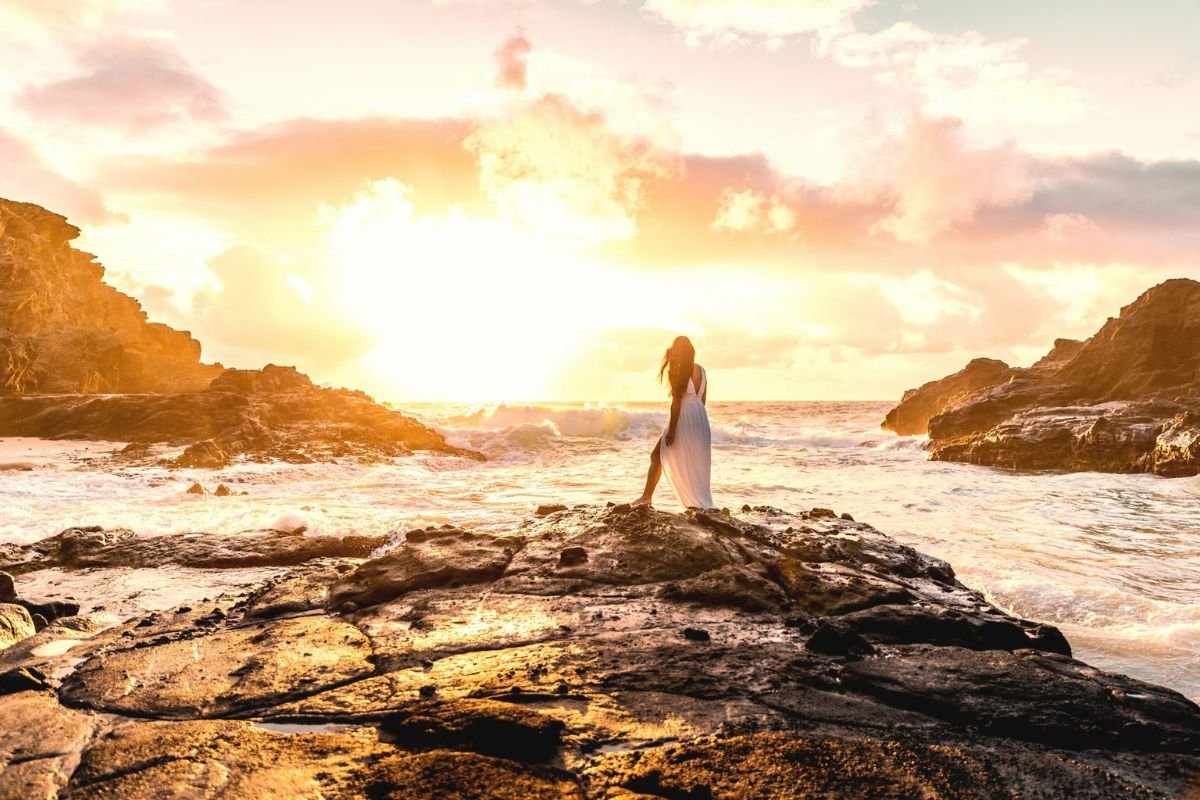 Person standing on a rock facing the horizon at sunset, symbolising living with integrity and staying true to personal values