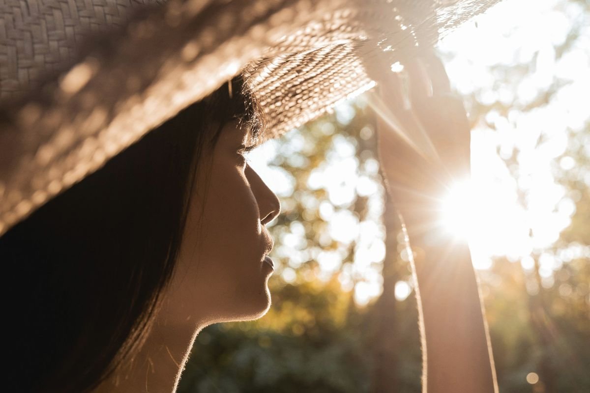Woman wearing a straw hat looking toward the sun, symbolising safe sun exposure and maintaining healthy vitamin D levels for long-term wellbeing.