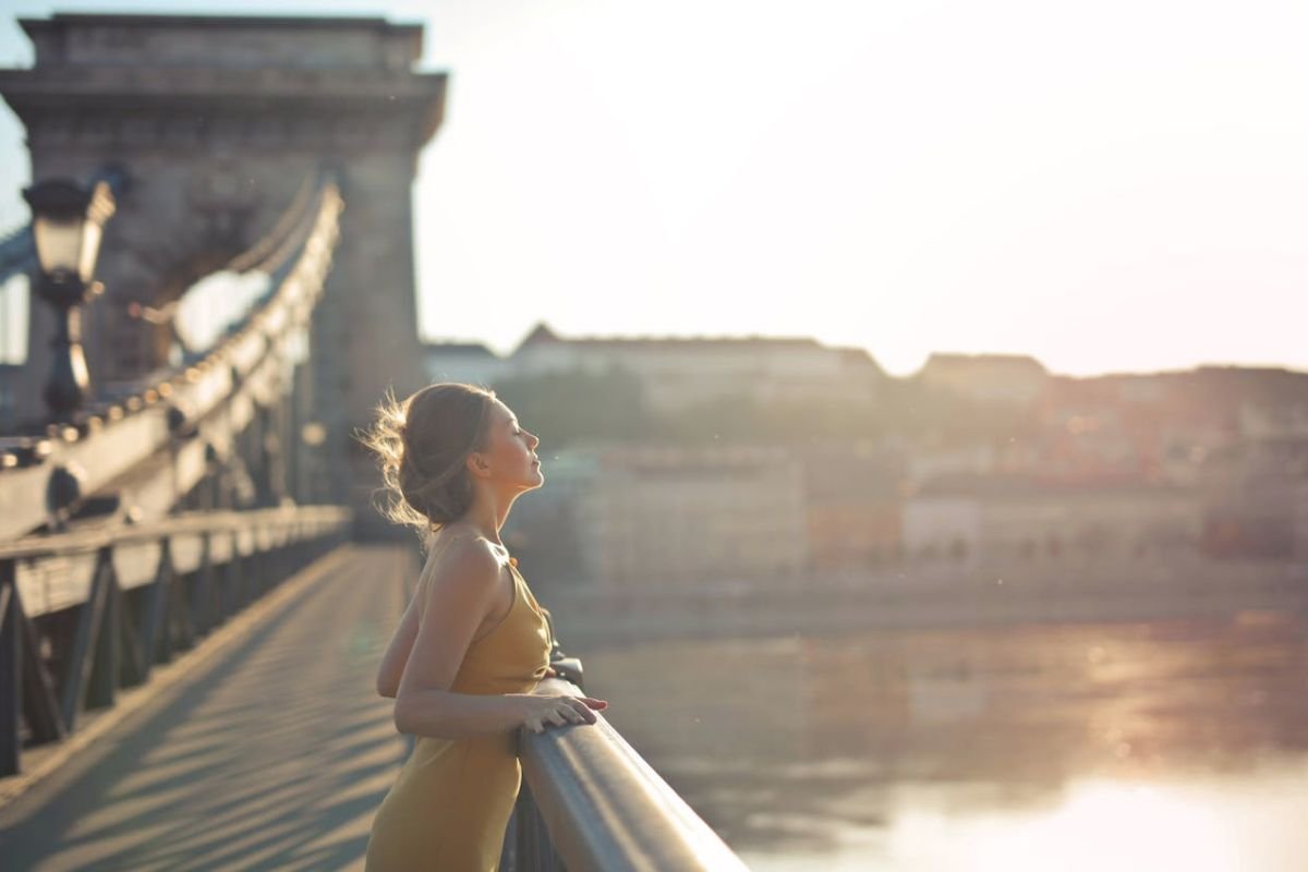 Woman standing by waterfront at sunset, symbolising emotional healing and self-awareness after relationship anxiety