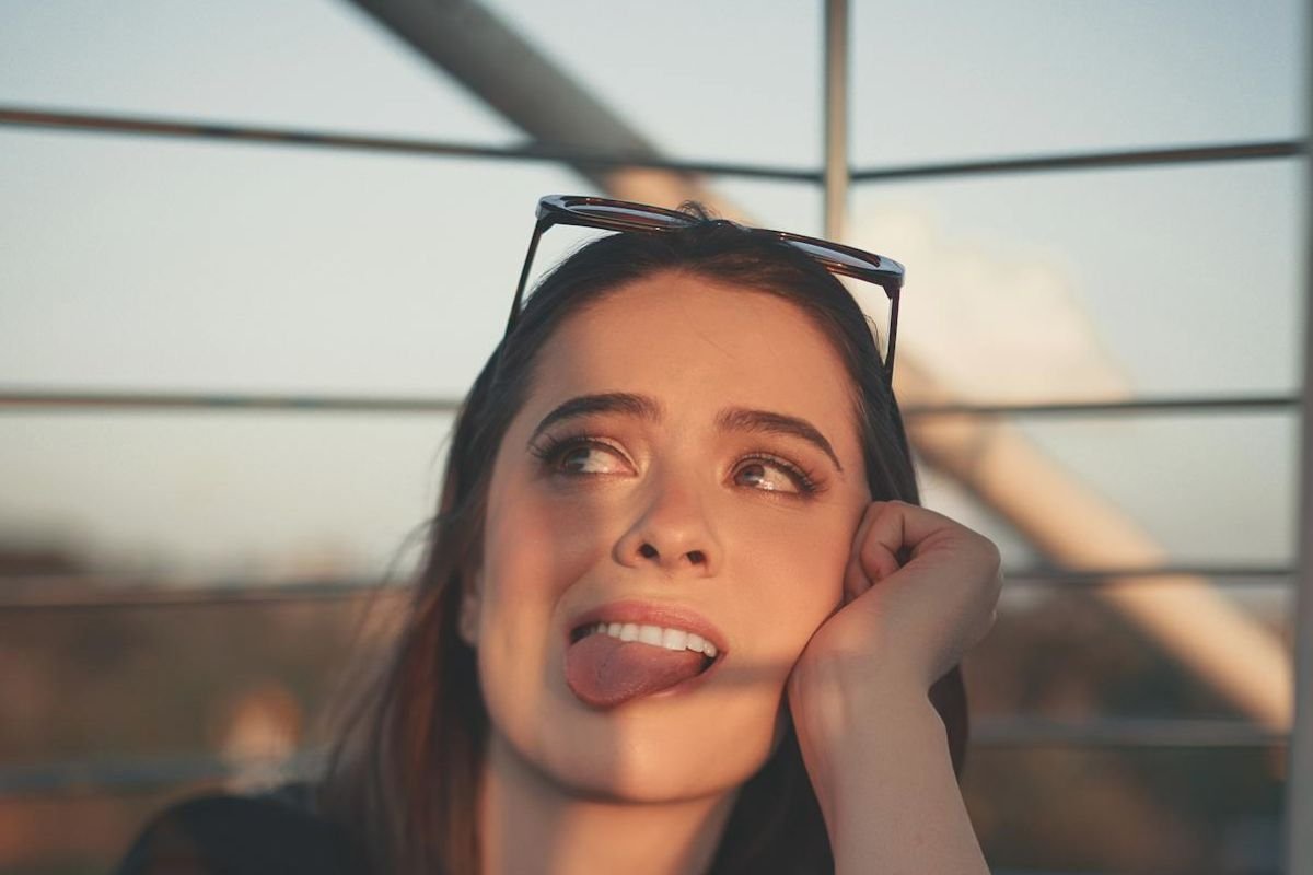 Young woman sticking out her tongue to show tongue cleaning importance for oral hygiene and breath care