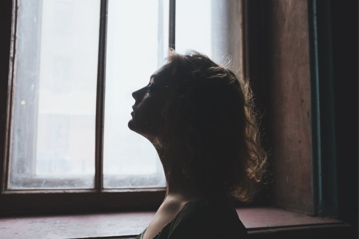 Woman looking out window feeling thoughtful, symbolising relationship anxiety and emotional reflection in love