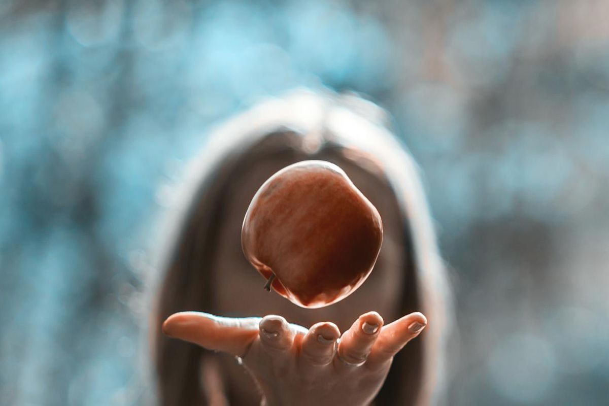 Person catching an apple in sunlight representing mental imagery, imagination, and the mind’s eye in people with and without aphantasia.