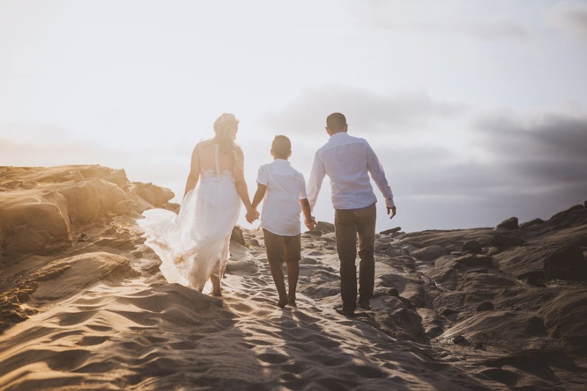 Family holding hands while walking along the beach at sunset, symbolising emotional support, healthy parenting, and family connection.