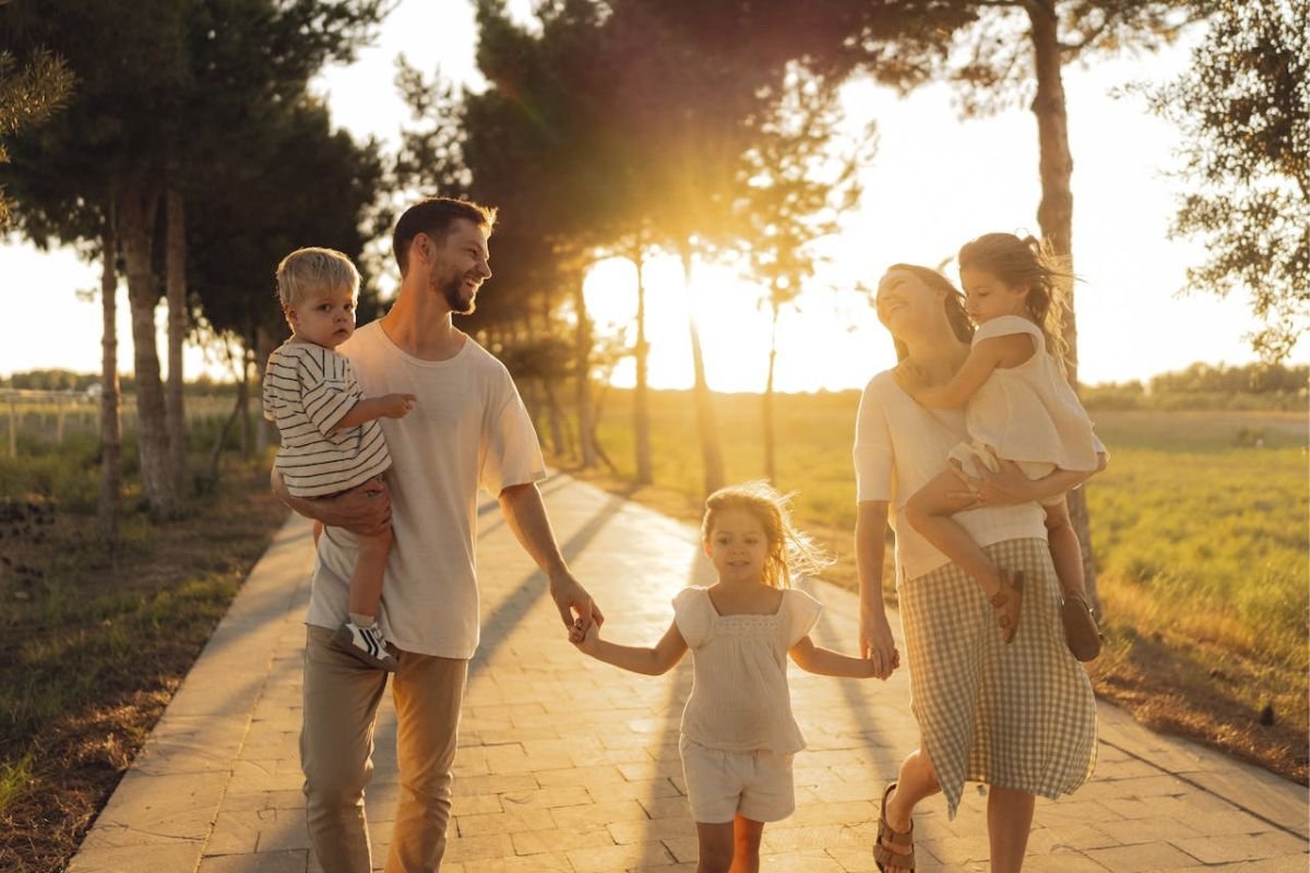 Parents walking closely with their children on a sunlit path, representing emotional resilience, healthy parenting, and strong family relationships.