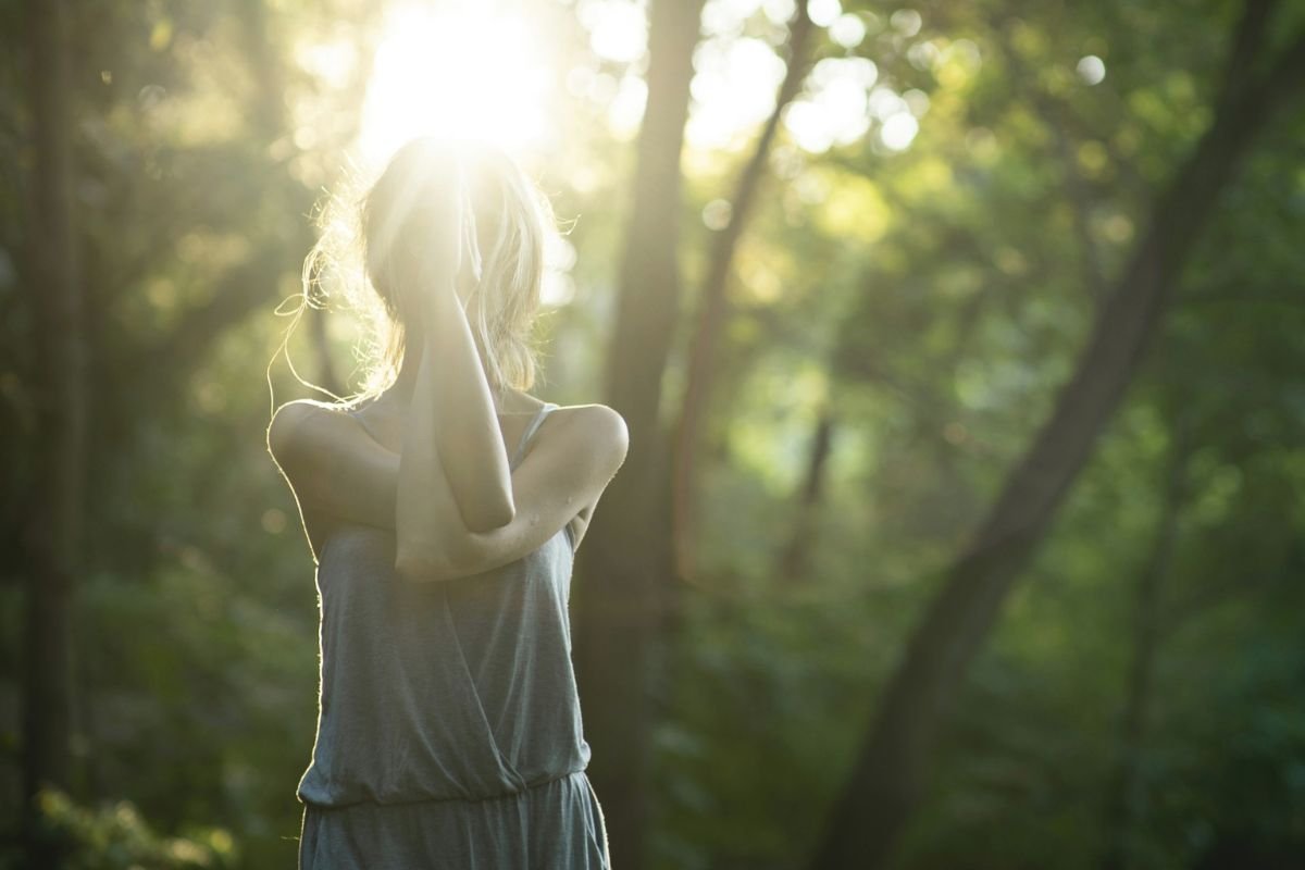 Woman standing peacefully in forest sunlight, symbolising balance, gut health, and the connection between zinc and emotional wellbeing.